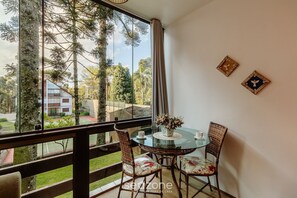 Uma varanda com mesa de vidro, cadeiras de vime e dois objetos decorativos fixados na parede.