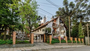 A residential building with a gated entrance, a sign indicating the name and address, and a paved driveway leading to the entrance. - Charming Apt in the Heart of Gramado! Rln0105 (Gramado)