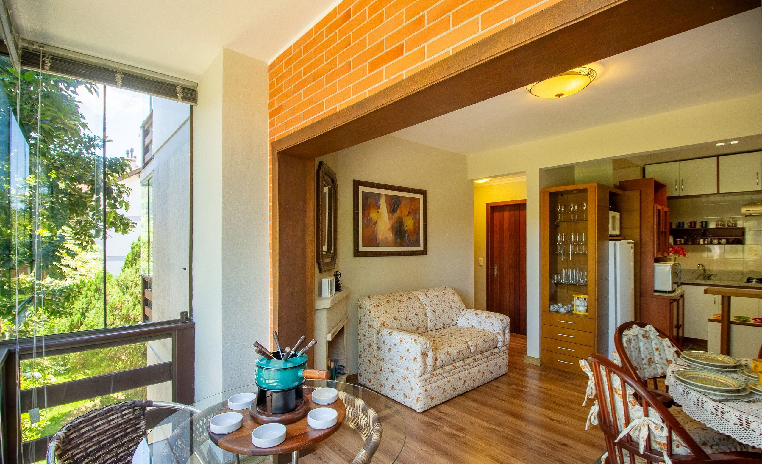 A spacious living area with a glass table, a sofa, and a kitchen in the background.