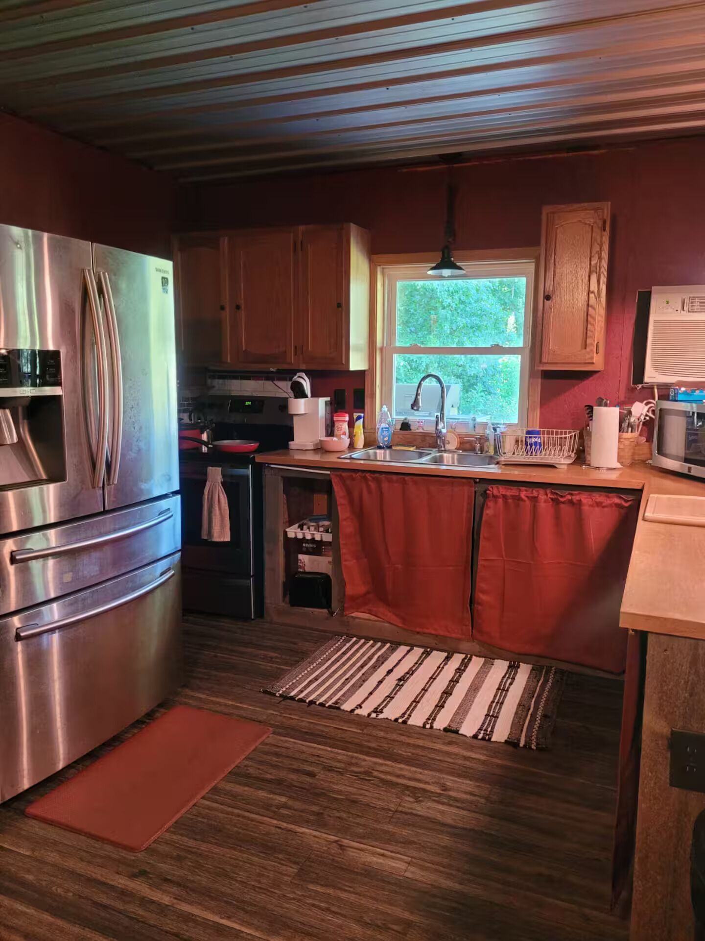 Una cocina compacta con un refrigerador de acero inoxidable, un horno empotrado y un lavamanos.
