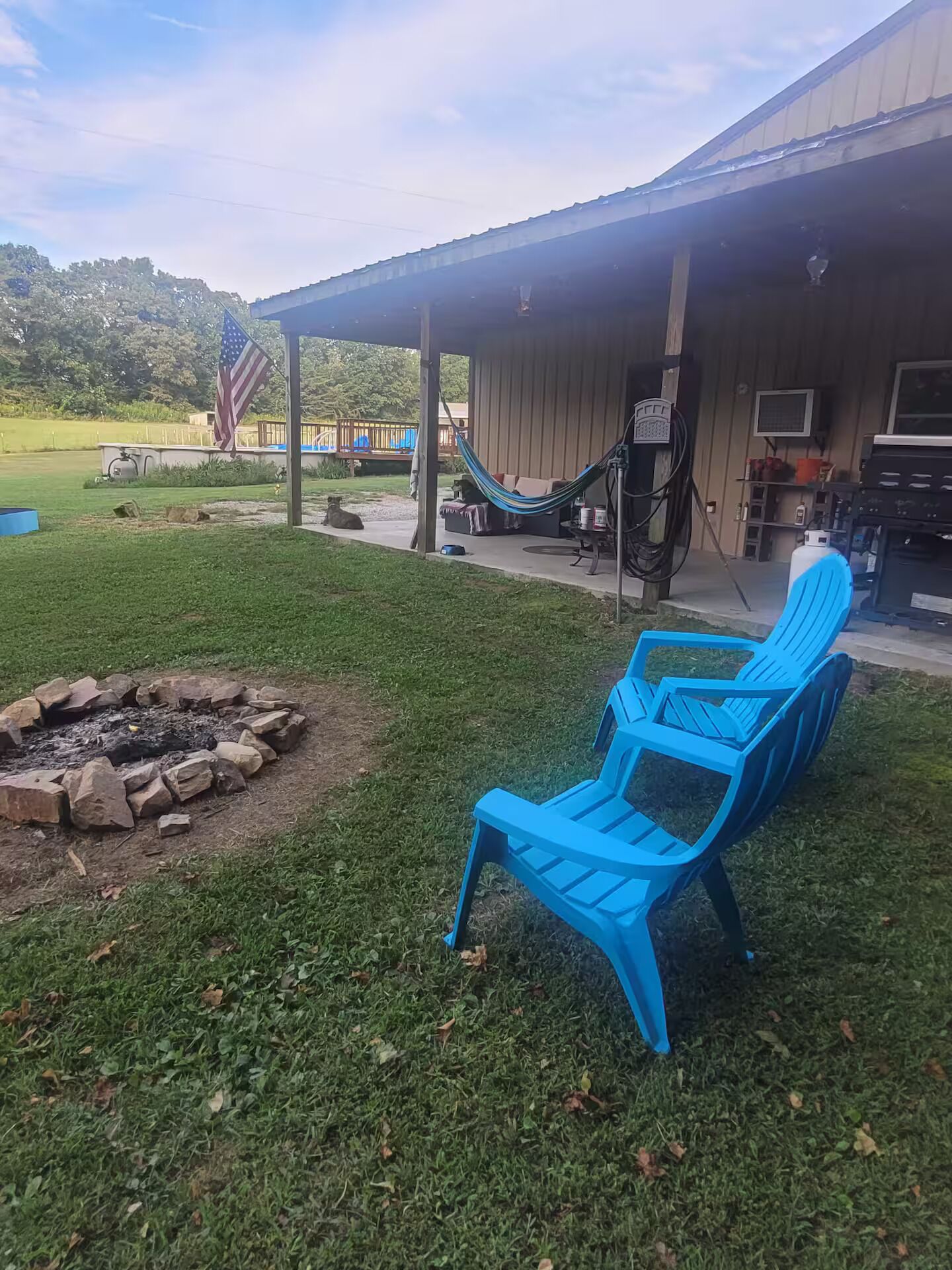 A patio area with blue chairs, a fire pit, and a hammock.