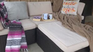 A cozy corner with a cushioned bench, a welcome pillow, a woven blanket, and a small table with a book and a mug. - The Hideaway - Private Mini-Farm Retreat for two (Evensville)