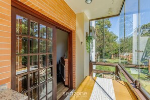 A room with a large window, a wooden table, and a view of the outdoors. - Apartment 300m From Black Lake Gramado/rs Rln0104 (Gramado)