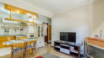 A compact living space with a kitchen area, dining table, chairs, a television, and a fireplace.