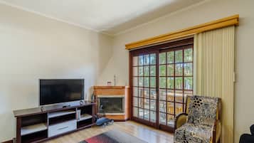 A living room with a TV, fireplace, and large window.