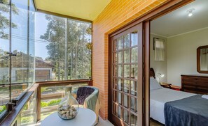 Een slaapkamer met een groot raam, een balkon en een bed met een blauwe sprei.