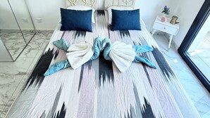 A bed with a patterned bedspread, two pillows, and towels arranged in a bow shape. - Villa Zinga—Pool, Garden, and Absolute Peace and Quiet (Béziers)