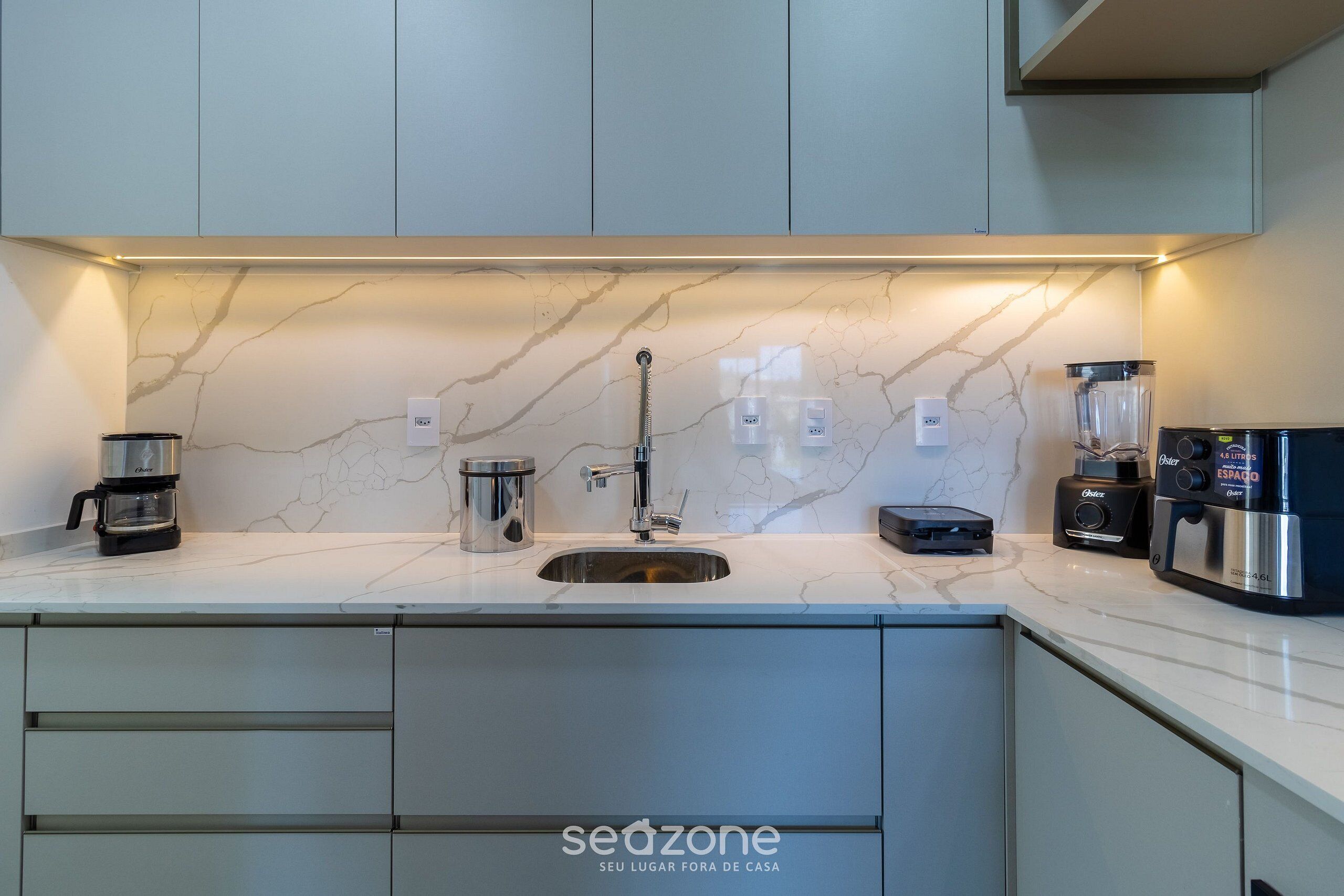 A modern kitchen with a marble backsplash, stainless steel appliances, and a built-in sink.