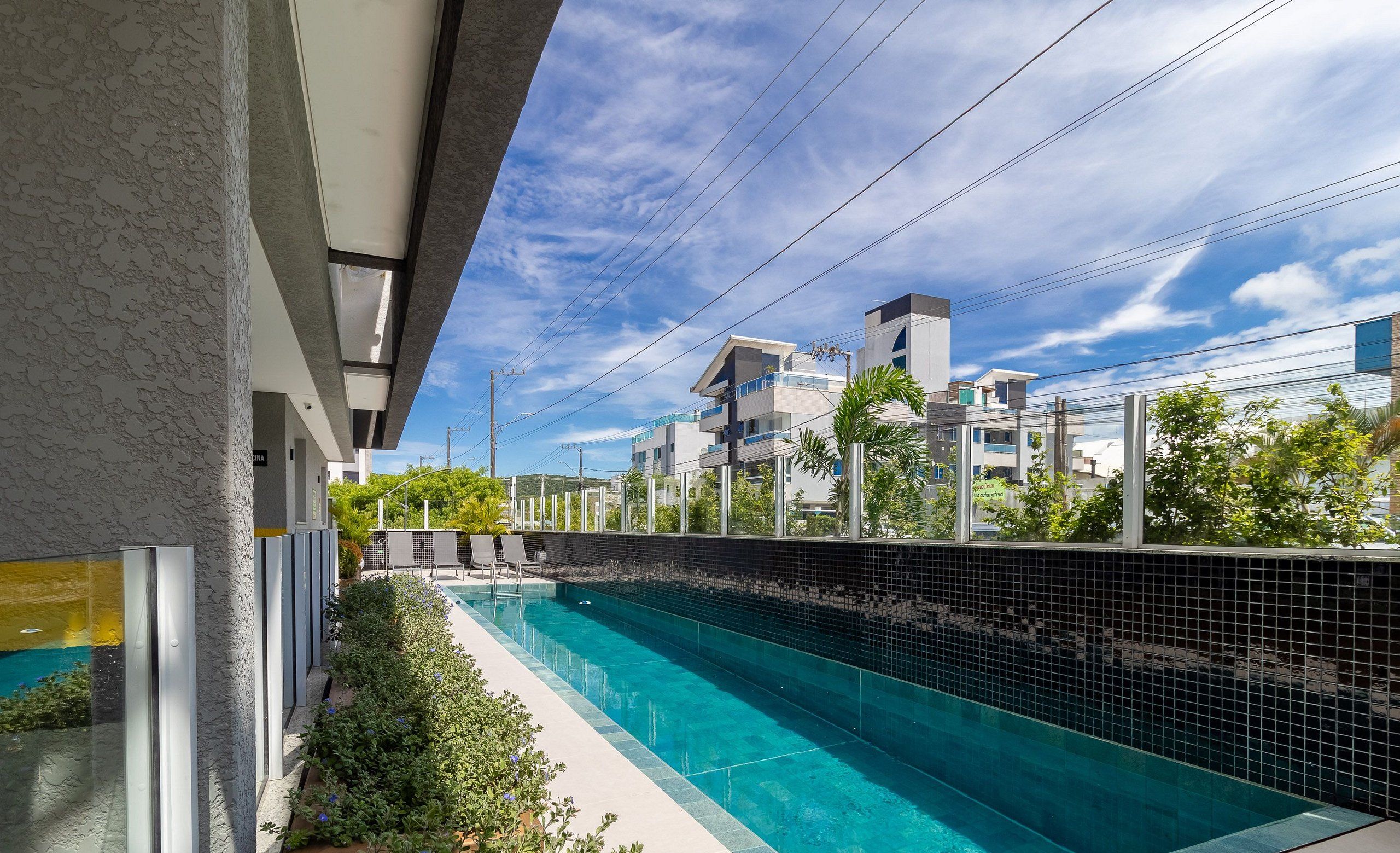 A swimming pool with a tiled edge, surrounded by greenery and modern buildings in the background.