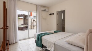 Een slaapkamer met een bed, een houten trap, een schuifdeur naar buiten en een airconditioning aan de muur.