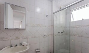 A bathroom with a sink, mirror, and shower.
