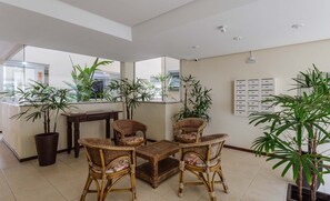 A spacious living area with wicker furniture, large windows, and potted plants. - Penthouse With Private Pool and Barbecue Rgp302 (Florianópolis)