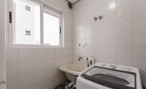 Un baño pequeño con ventana, un lavabo y una lavadora.