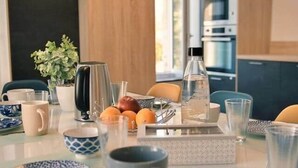 A modern kitchen with a central island, various kitchen appliances, and a dining area with chairs and a table set for a meal.