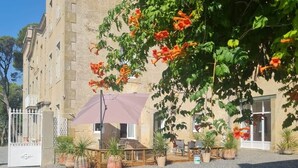 A building with a gravel courtyard, outdoor seating, and potted plants.