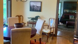 Un comedor con candelabro, sillas de madera, una mesa y una alfombra.