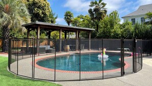 A circular pool with a surrounding fence, a covered seating area, and a gazebo. - Wine Country Home (Napa)