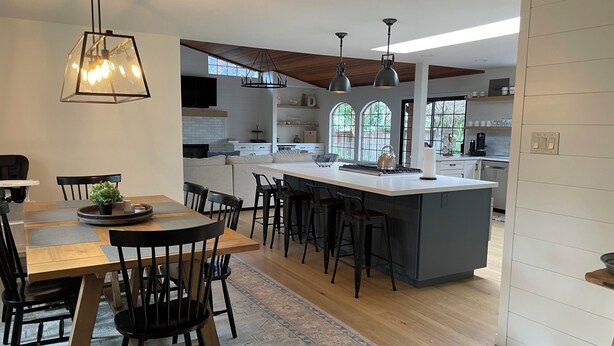 A modern kitchen with a central island, pendant lighting, and a dining area with a round table and chairs. - Wine Country Home (Napa)