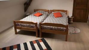 A bedroom with two wooden beds, a skylight, a wooden door, and a small round rug. - Apartment 'À L'Aujardière' with Shared Garden and Wi-Fi (Durtal)