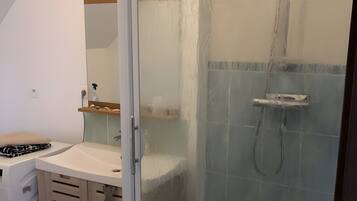 Una ducha con puerta de cristal, un armario de madera y un espejo.
