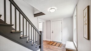 Een modern interieur met een trap, een witte deur en een bankje.