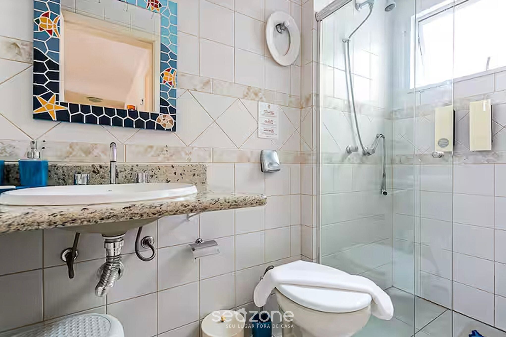 A bathroom with a sink, mirror, toilet, and shower.