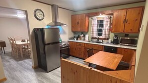 A compact kitchen with wooden cabinets, a refrigerator, a microwave, and a sink.