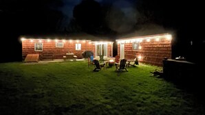 A wooden cabin with a patio area, outdoor seating, and a fire pit.