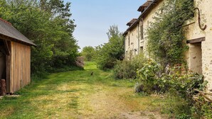 A narrow rural path flanked by buildings and greenery. - Guest Room 'Cocon' with Shared Garden and Wi-Fi (Durtal)