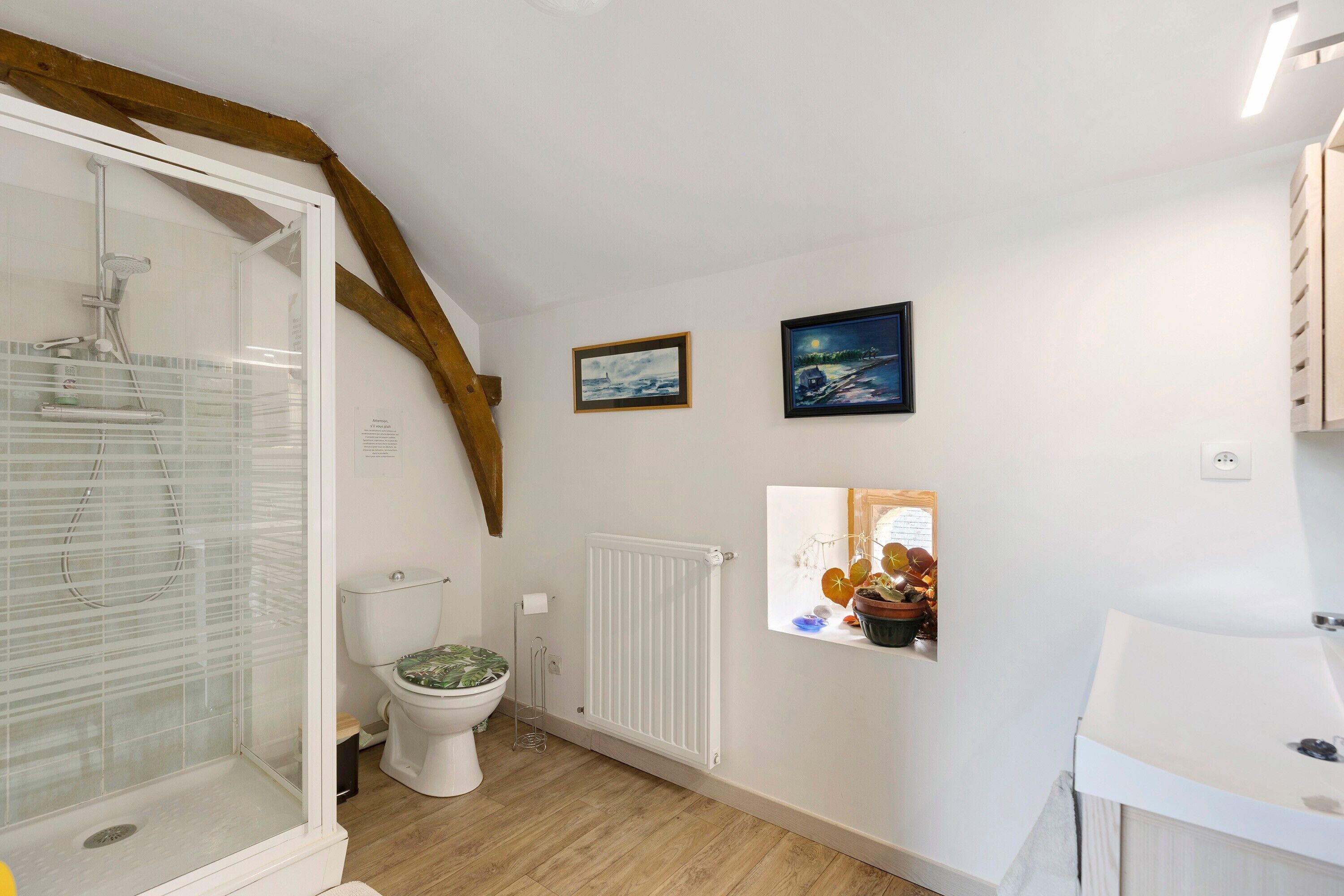 Une salle de bain équipée d’une douche, de toilettes, d’un radiateur et d’un lavabo.