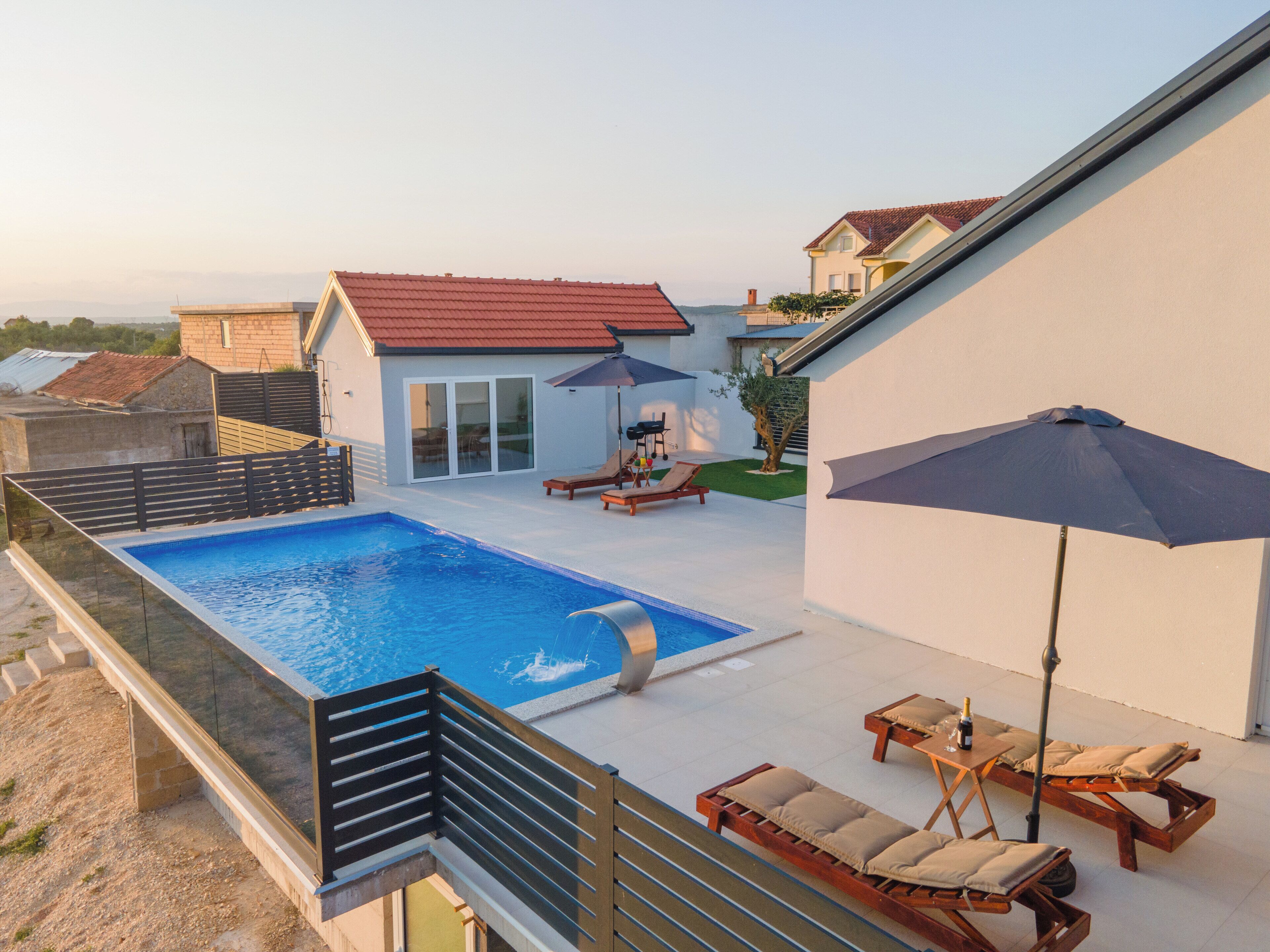 A rooftop swimming pool with lounge chairs and a barbecue area.