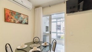 Un coin repas avec une table en verre, quatre chaises et un tableau accroché au mur.