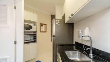 A compact kitchen with a refrigerator, microwave, and oven.