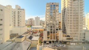 A high-rise building with multiple balconies, a modern architectural design, and a clear view of the surrounding urban area. - Full Studio 650m From Meia Praia Rgor0025 (Itapema)