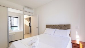 Een hotelkamer met een bed, nachtkastje, kledingkast en raam.