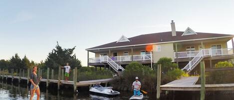 A waterfront property with a dock, paddleboards, and a small boat.