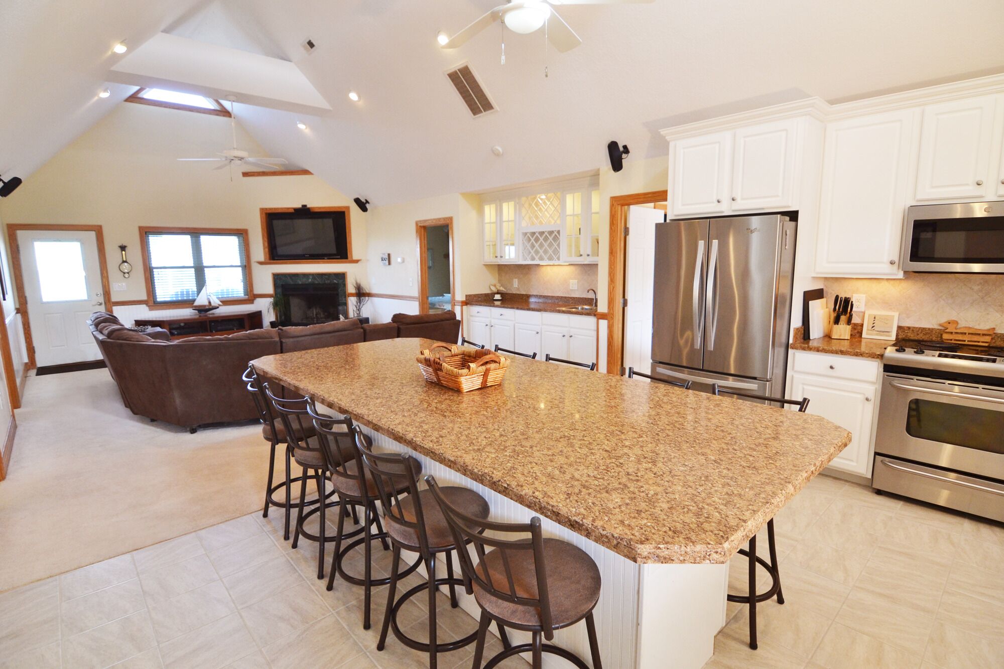 A spacious kitchen with granite countertops, stainless steel appliances, and a central island with bar stools.