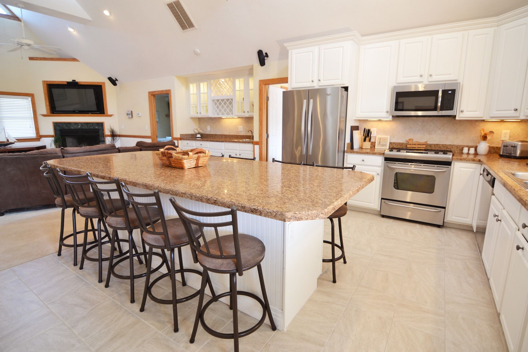 A modern kitchen with white cabinets, stainless steel appliances, and a granite island with bar stools.