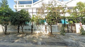 Un edificio residencial con fachada blanca, una cerca blanca y varios árboles en la parte delantera.