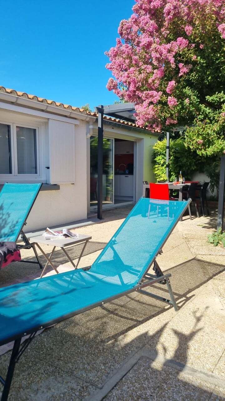 Un espace aménagé au bord de la piscine, comprenant deux chaises longues, une petite table et un bâtiment doté d’un toit recouvert de tuiles.