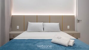 Een hotelkamer met een bed, nachtkastje en een wandlamp.
