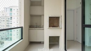 Een moderne keuken met witte kastjes, een ingebouwde oven en een klein raam.