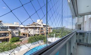 Ein Wohngebäude mit mehreren Etagen, einem Swimmingpool und Blick auf umliegende Grünflächen und weitere Gebäude.