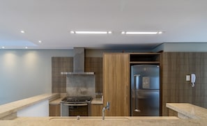 Eine moderne Küche mit Einbauherd, Edelstahlkühlschrank und Holzschränken.