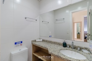 A modern bathroom with white tiles, a granite countertop, a sink, a mirror, and a toilet. - Apt w/ Side sea View, Seaside Condominium Rap0306 (Florianópolis)