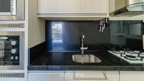 Et moderne køkken med rustfrie hvidevarer, en sort bordplade og en indbygget vask.