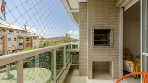 En balkon med gelænder af glas, en murstenspejs og en fletstol.