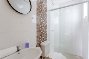 A bathroom with a white sink, a mirror, a shower, and a toilet.