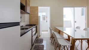 Una cocina moderna con comedor, armarios blancos y una mesa de vidrio.