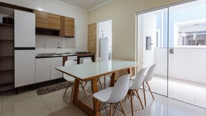 Una cocina moderna con armarios blancos, una mesa de comedor de vidrio y sillas blancas.